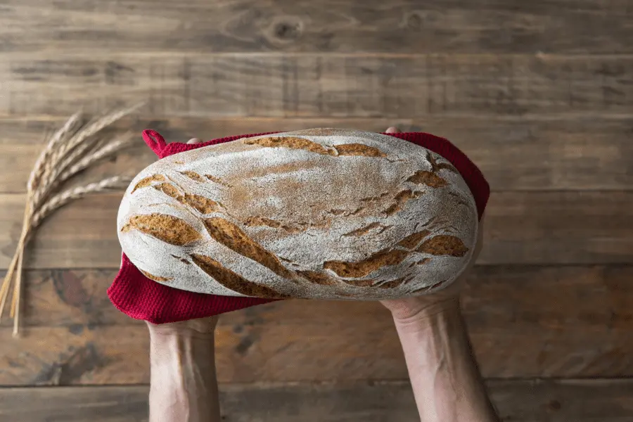 dos manos de un panadero sosteniendo un pan de pueblo