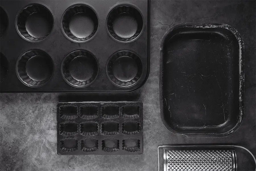 Moldes y bandejas para hornear colocados sobre una mesa de cocina color gris