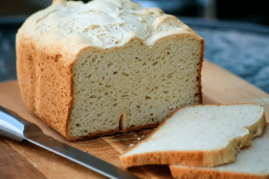 Pan sin gluten siendo rebanado en una tabla de cortar sobre una mesa