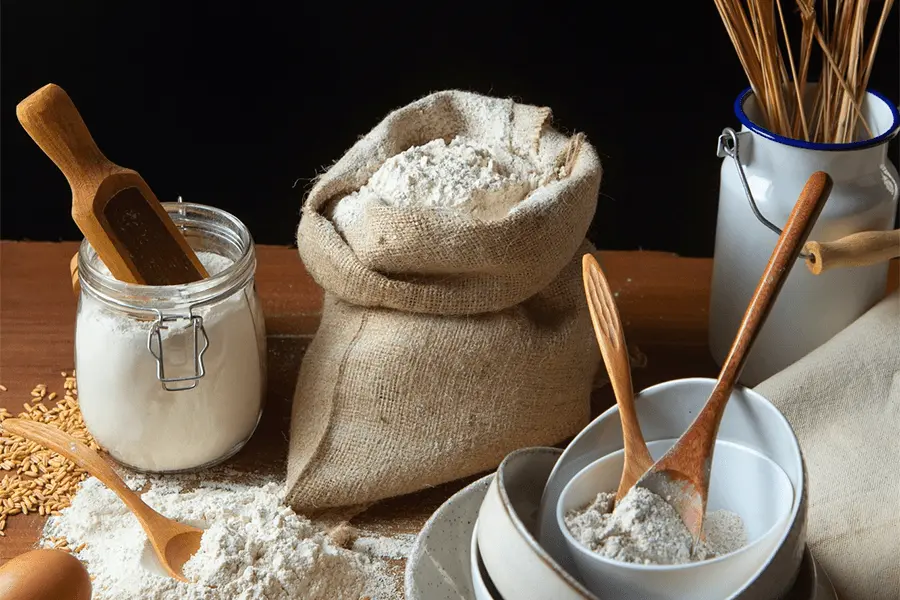 Vista frontal de ingredientes para preparar pan colocados en una mesa de madera