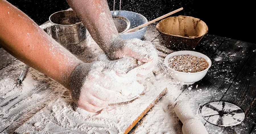 Mano masculina de panadero amasando masa en una cocina