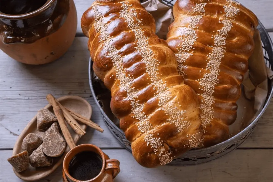 Pan de feria sobre una canastilla con panela y canela a su costado