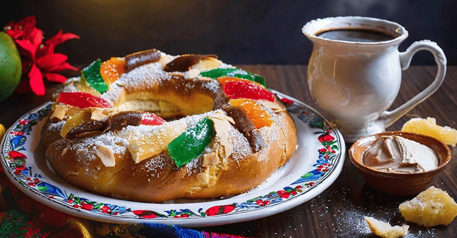 Primer plano de una rosca de reyes servida en un plato, acompañada de un café de olla